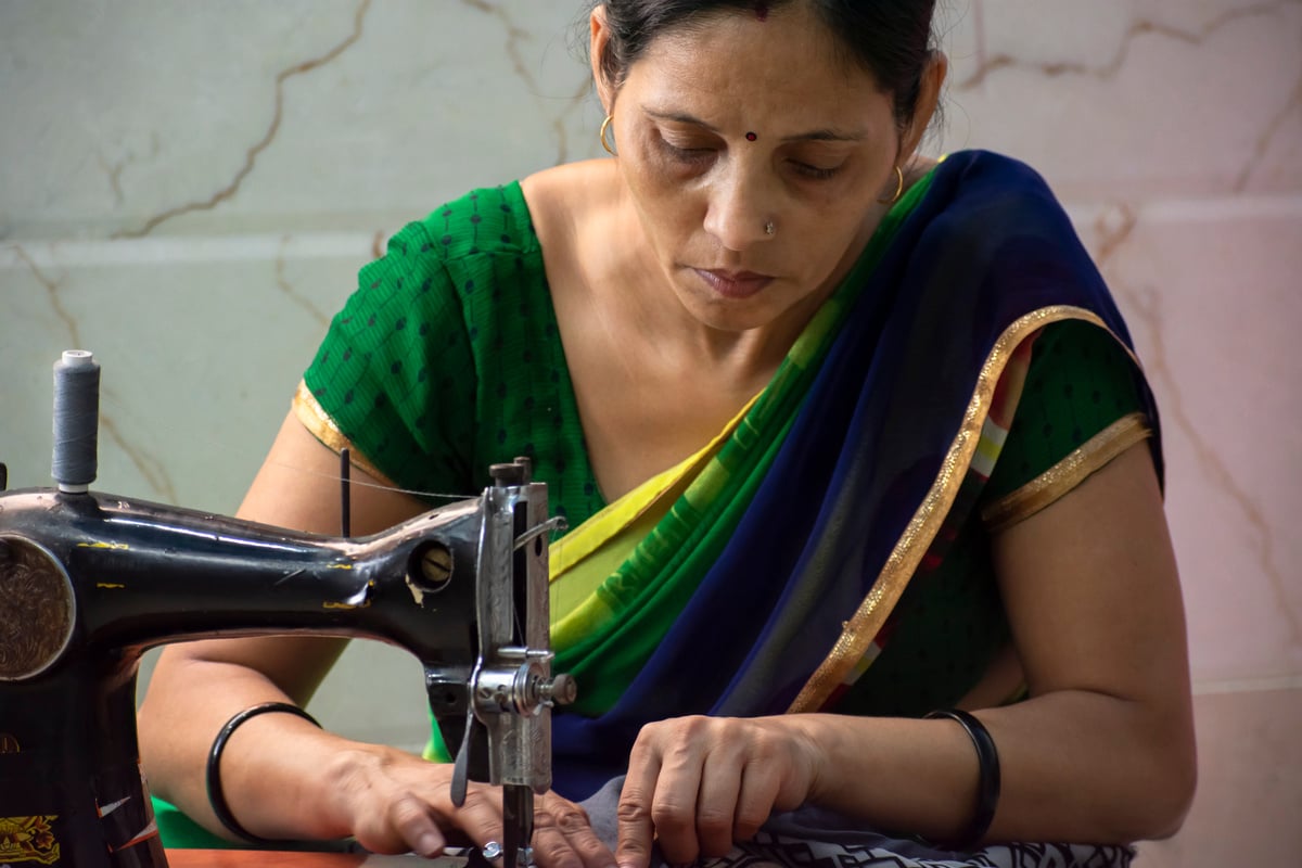 Indian women stitching cloths by machine at home